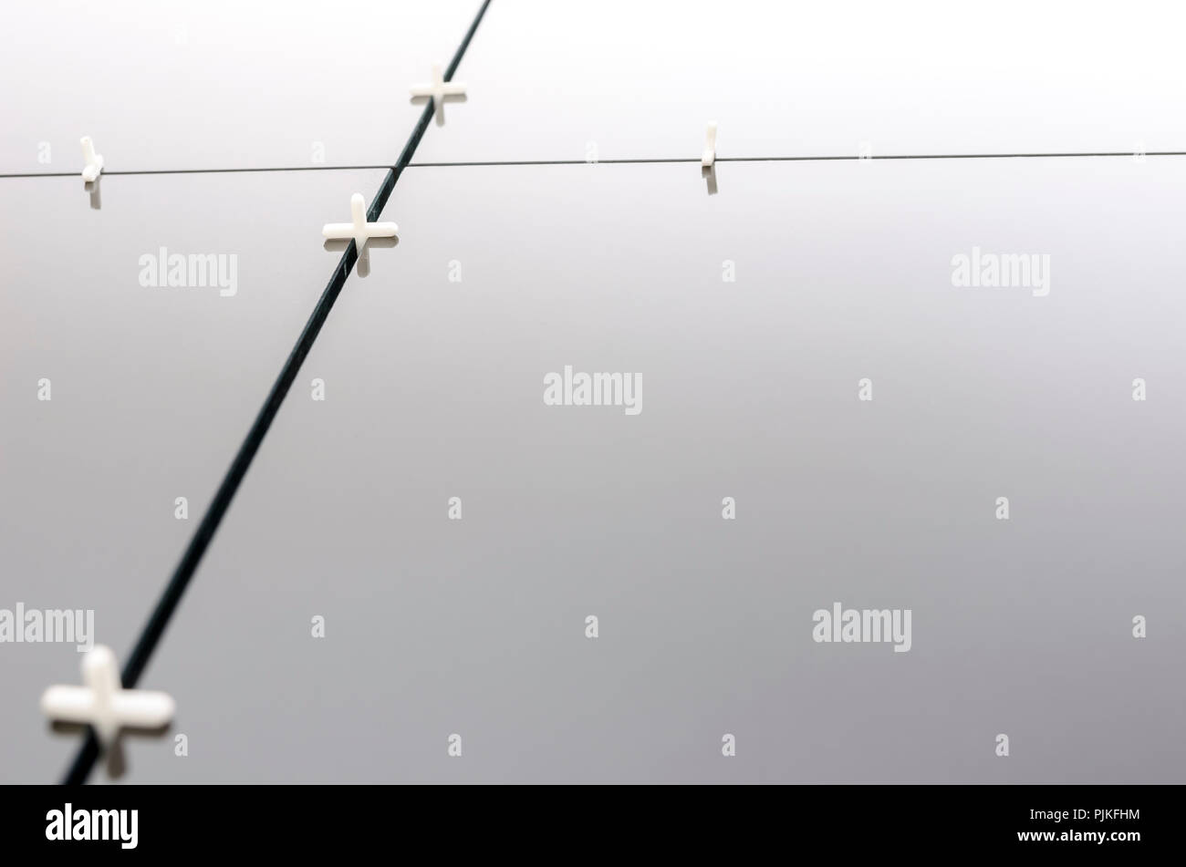 Closeup of unfinished black ceramic tiles with tile spacers. Concept of