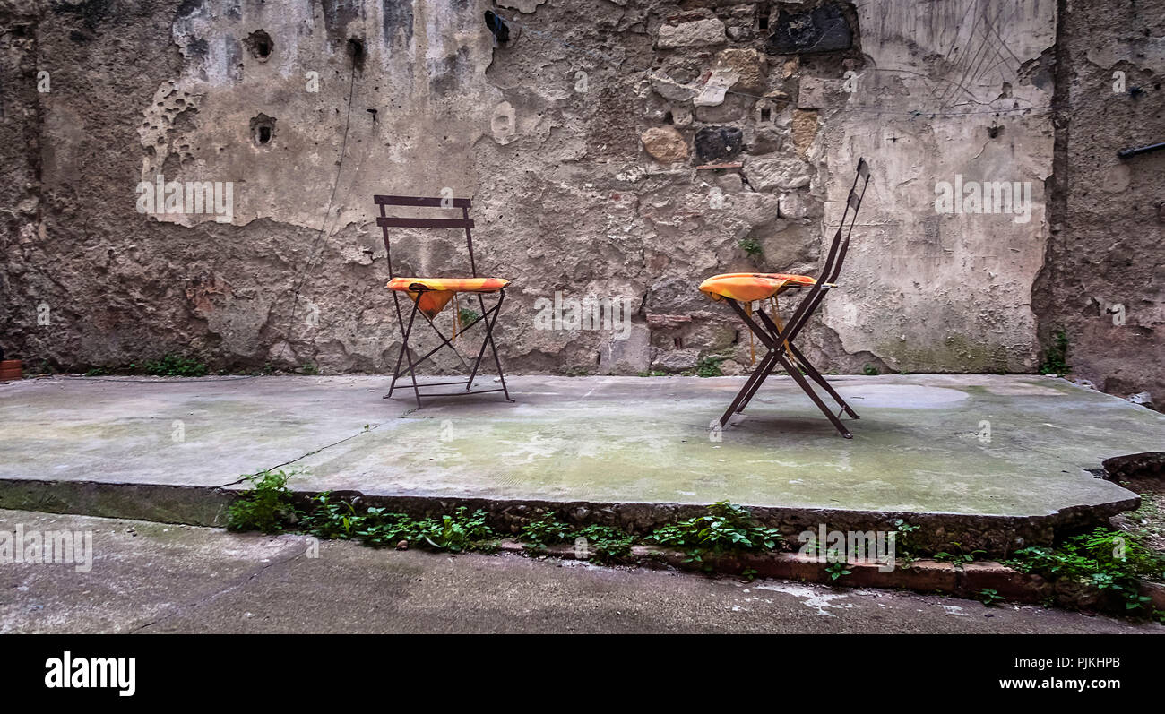 Two metal chairs with pillows in an old backyard Stock Photo