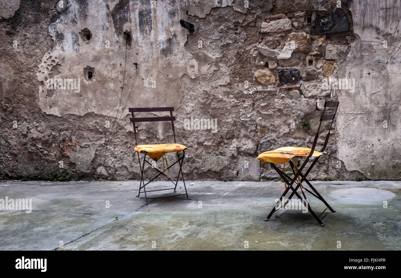 Two metal chairs with pillows in an old backyard Stock Photo