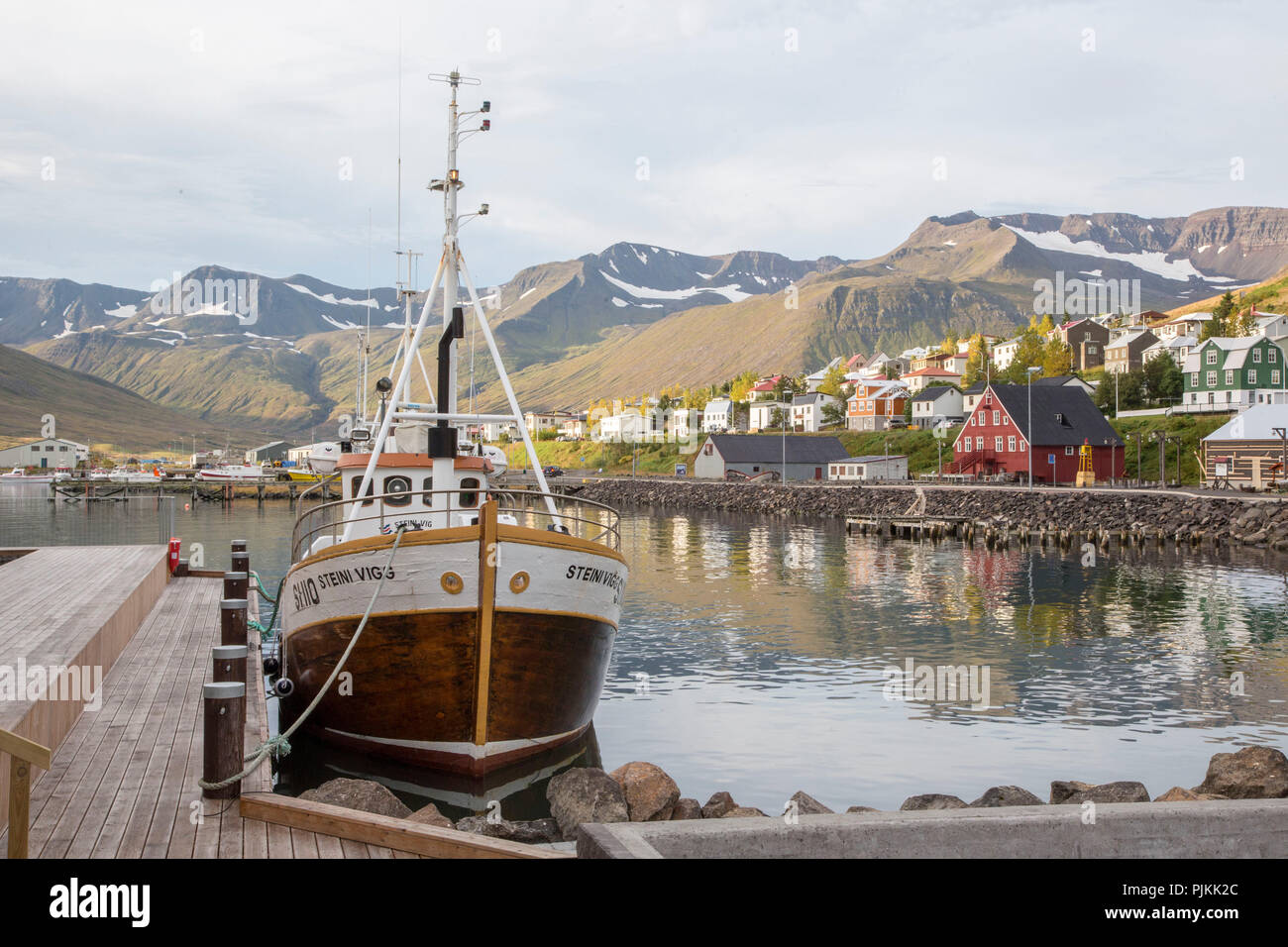 Iceland, North Iceland, Fishing boat on quay, Colorful houses, Mountains in the background, Red house, Reflection in the water, Sunshine, Stock Photo