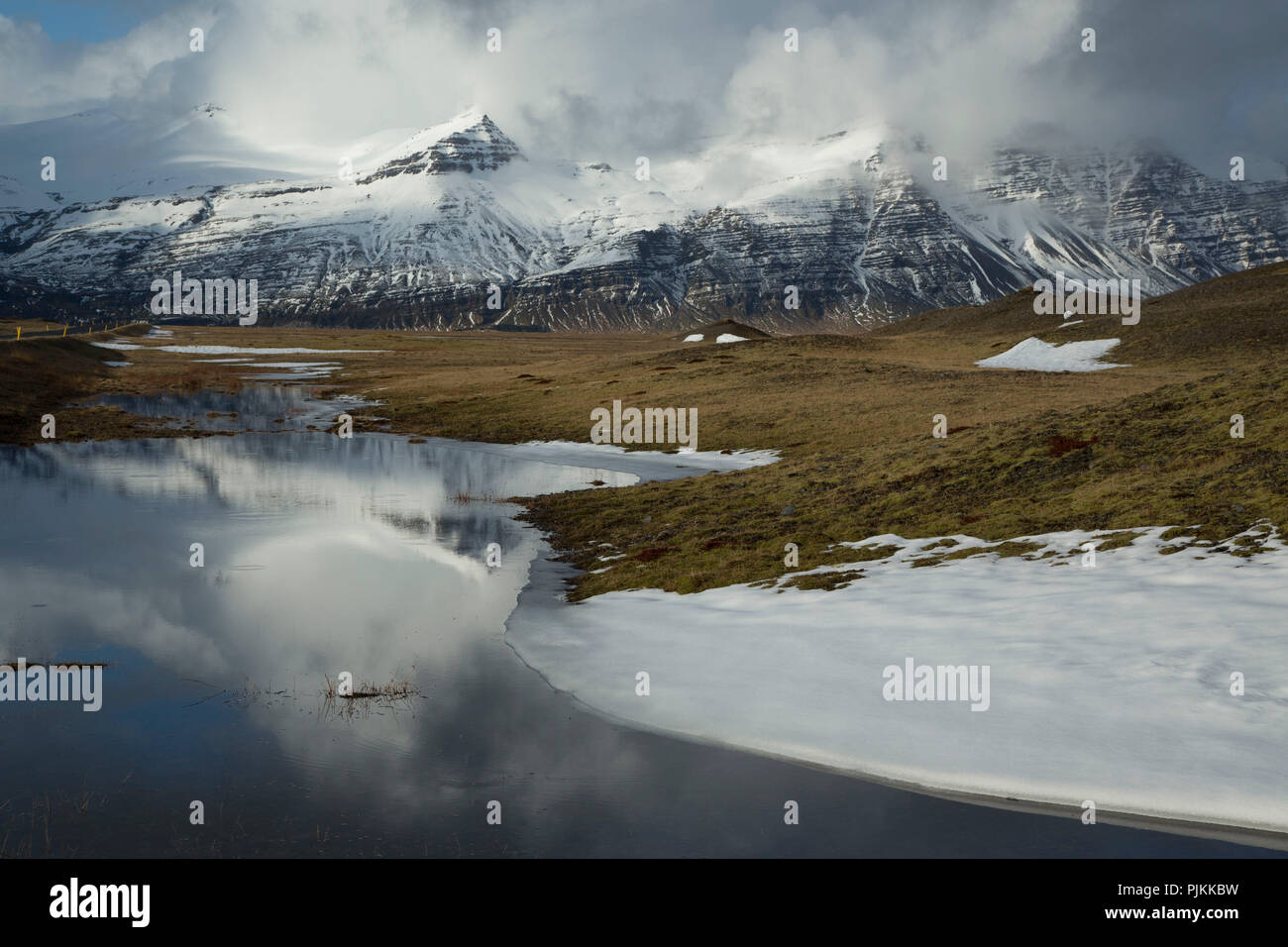 Iceland, lake, snowy mountains, wild cloud mood, reflection in the water, early spring Stock Photo