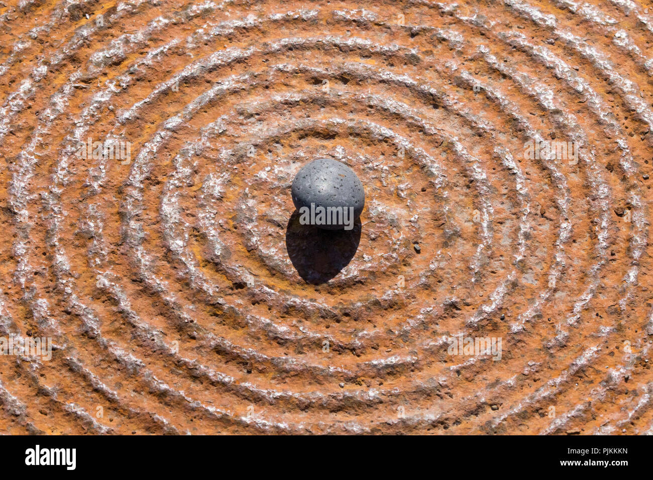 black stone on concentric circles, iron plate, Stock Photo