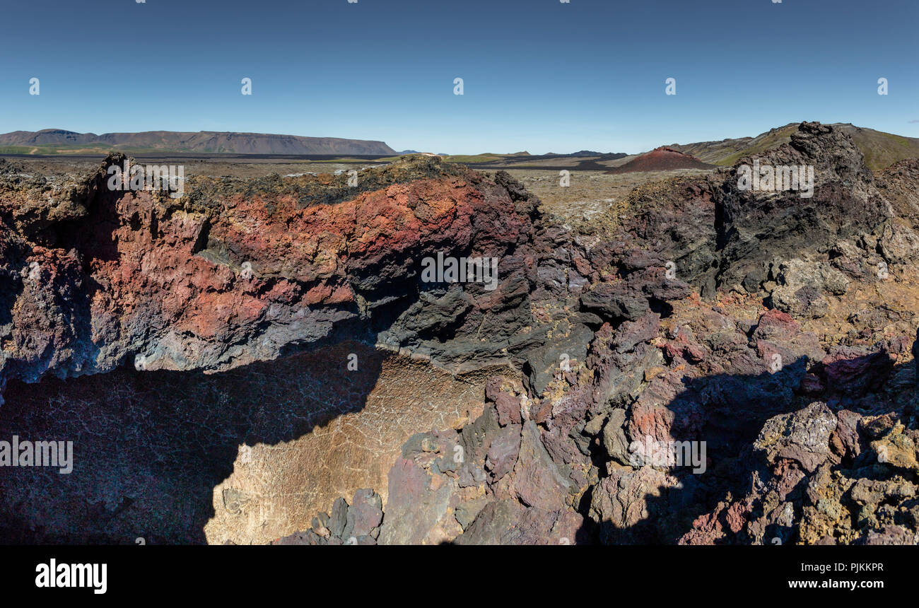 Iceland, Krafla volcano, fresh lava fields in the Krafla caldera, red and black lava, small volcanic cone in the background, blue sky Stock Photo