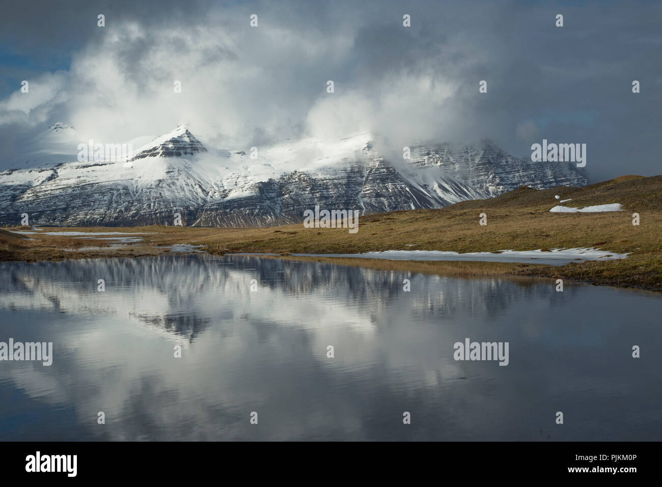 Iceland, lake, snowy mountains, wild cloud mood, reflection in the water, early spring Stock Photo