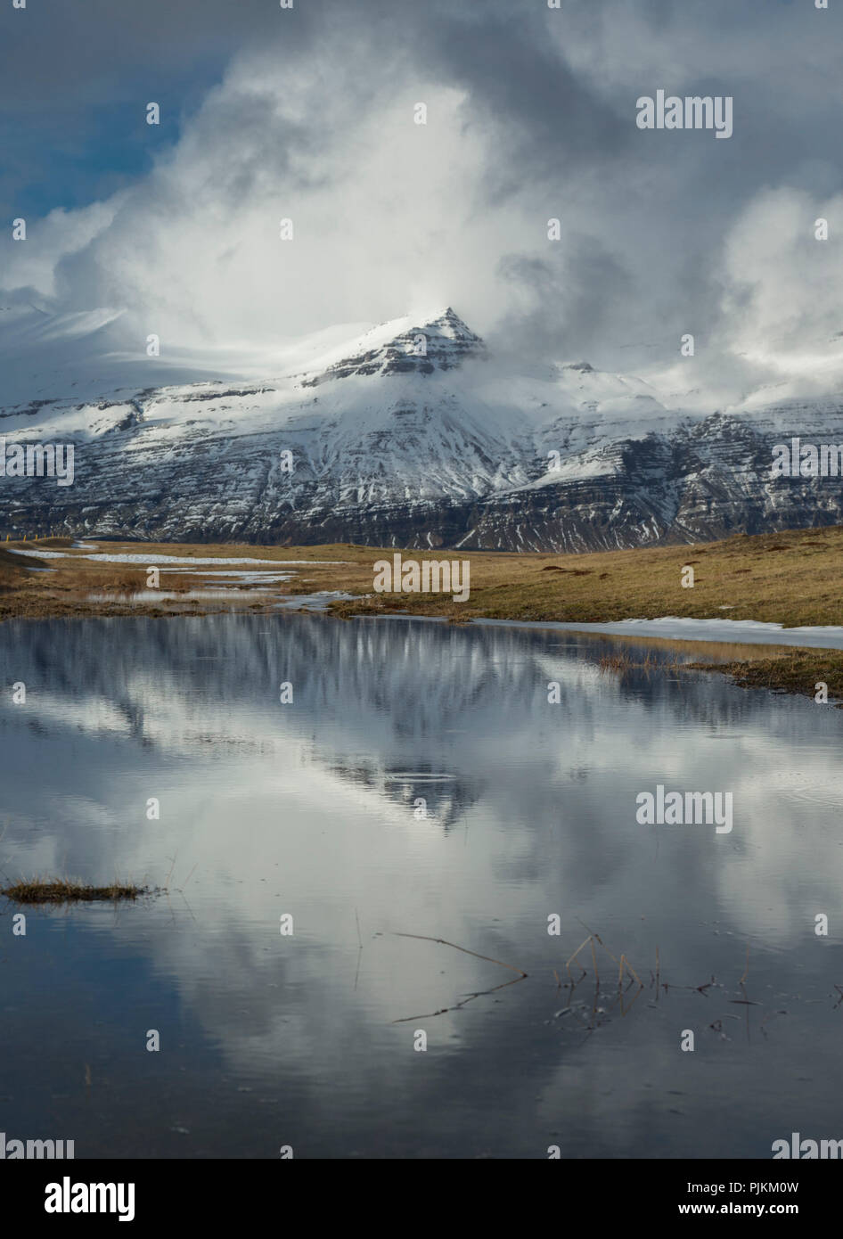 Iceland, lake, snowy mountains, wild cloud mood, reflection in the water, early spring Stock Photo