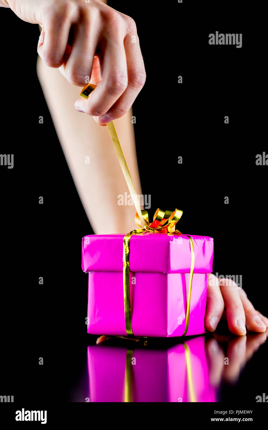 Closeup of female hand opening pink wrapped gift box. Isolated over ...