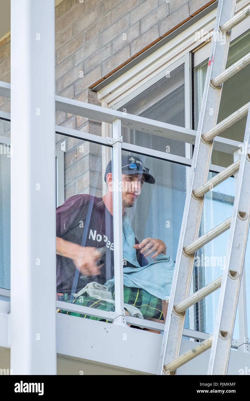 Male window cleaner washes the glass on the balcony of a building. Stock Photo