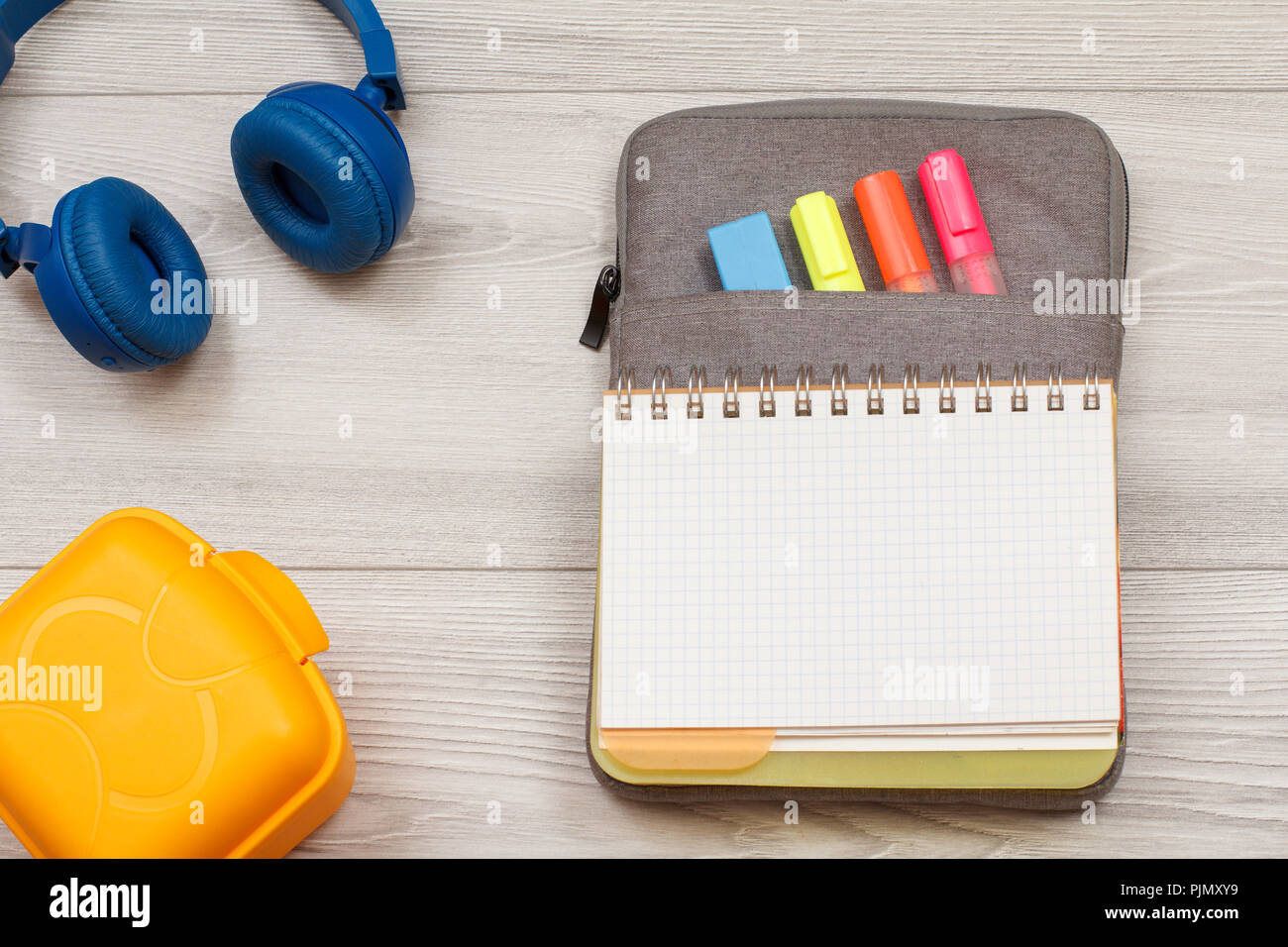 School supplies. Yellow sandwich box, headphones, open exercise book on  bag-pencil case with color felt pens and marker on grey wooden boards. Top  vie Stock Photo - Alamy