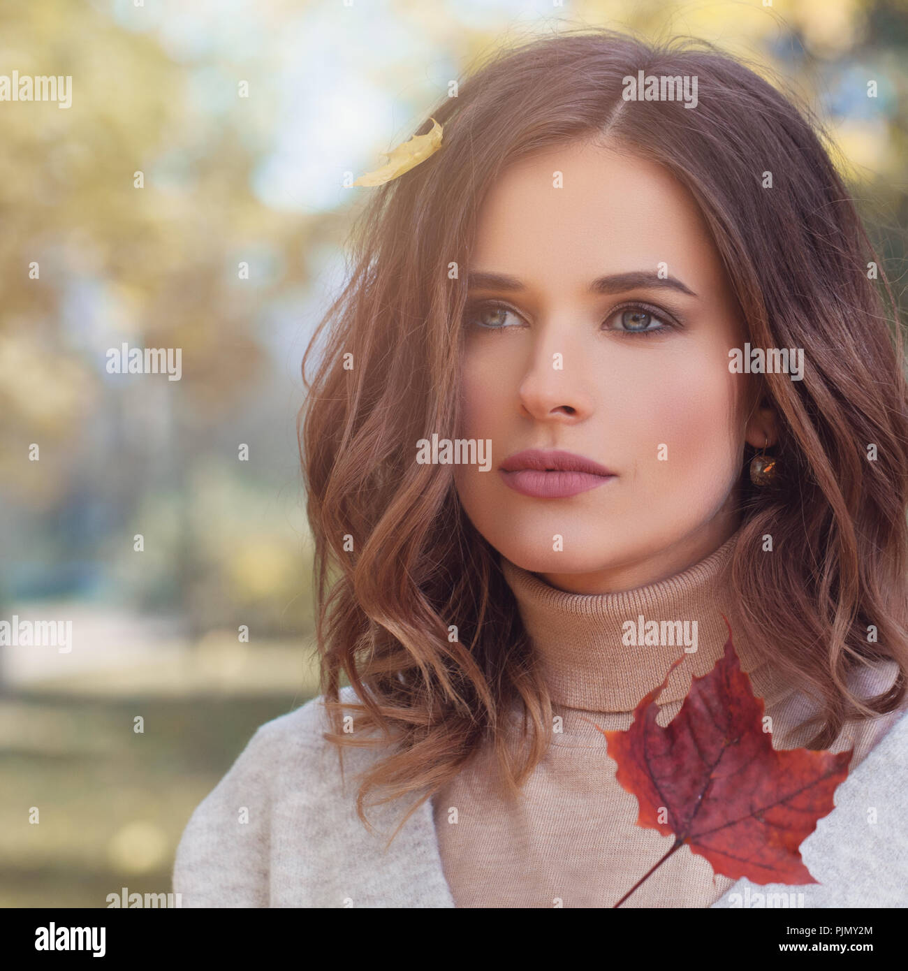 Autumn beauty. Young woman with fall leaves in wavy hair outdoor ...