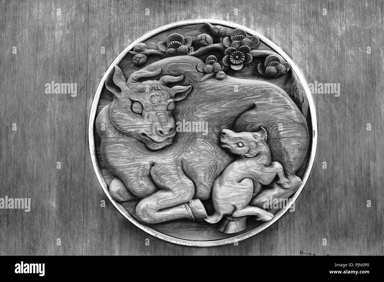 Ox messenger deity and playful calf temple door relief Stock Photo