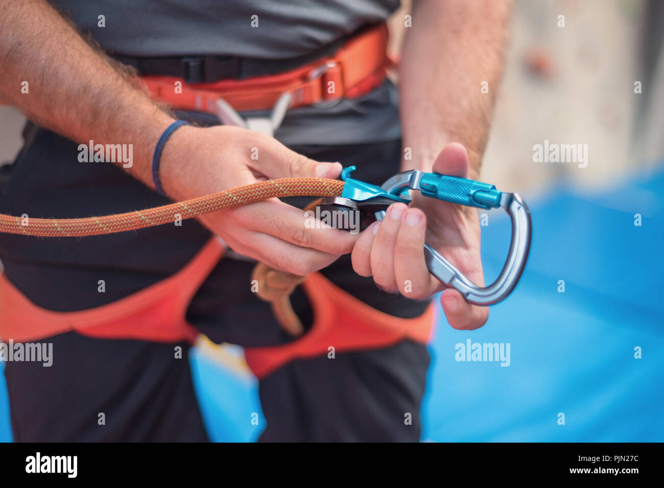 Rock wall climber wearing safety harness and climbing equipment indoor, close-up image Stock Photo