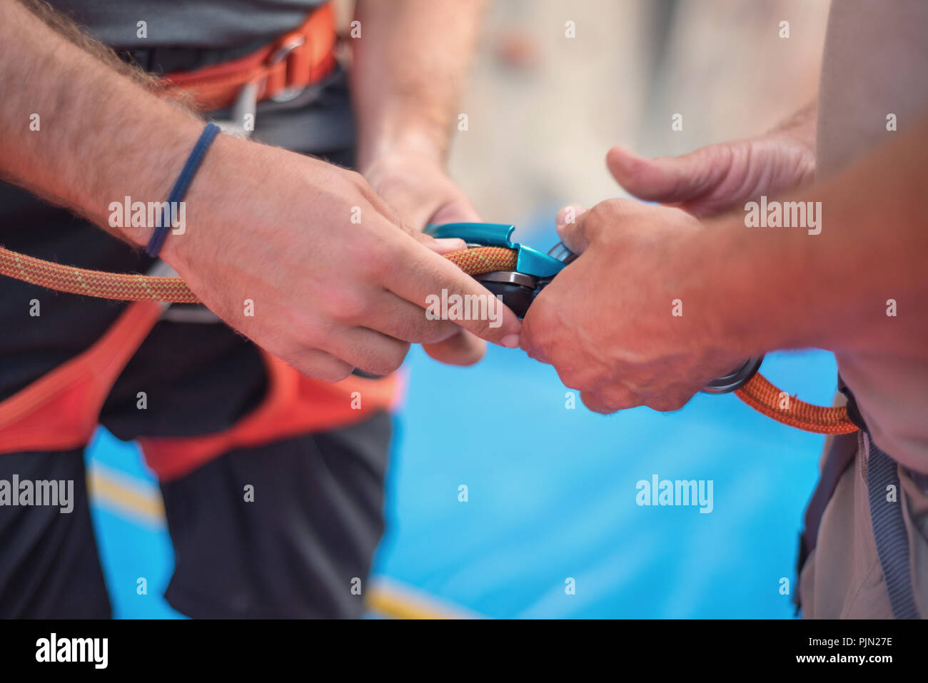 Rock wall climber wearing safety harness and climbing equipment indoor