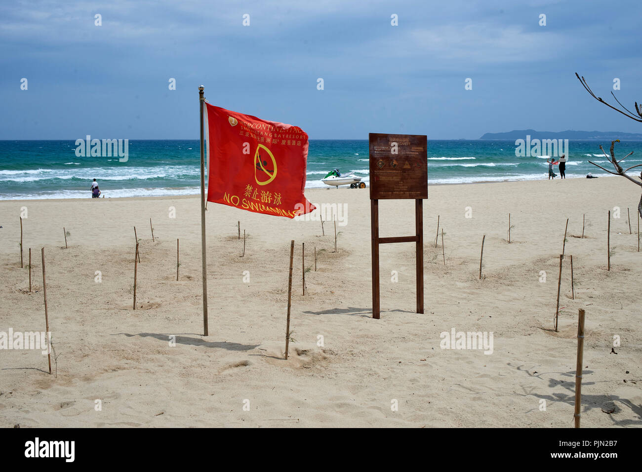 Sandy beach at the seaside, Sanya, on a windy summer day. 'No swimming' flags visible Stock Photo