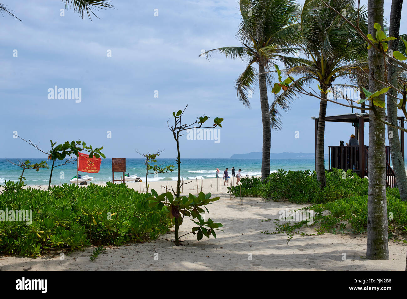 Sandy beach at the seaside, Sanya, on a windy summer day. 'No swimming' flags visible Stock Photo