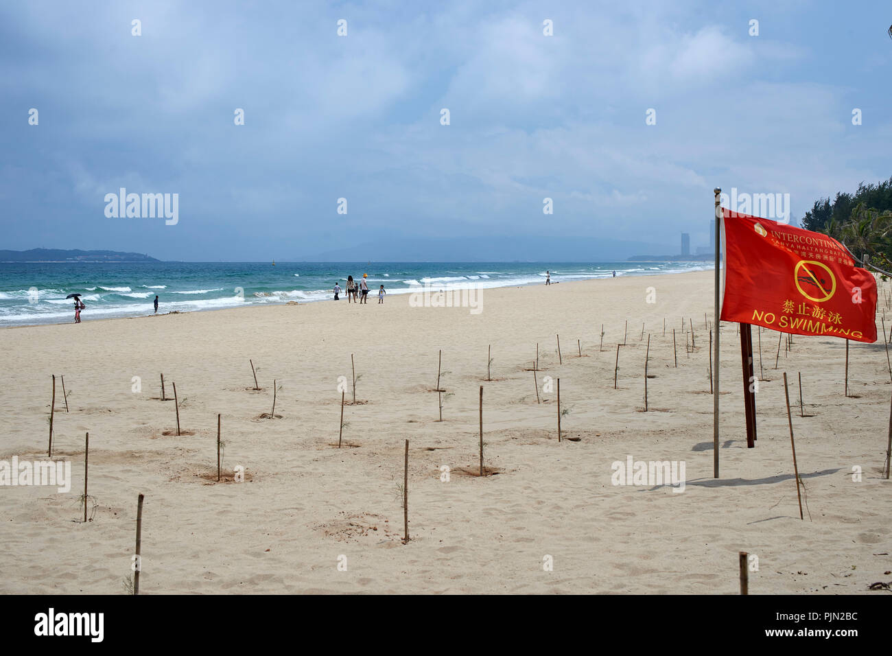 Sandy beach at the seaside, Sanya, on a windy summer day. 'No swimming' flags visible Stock Photo