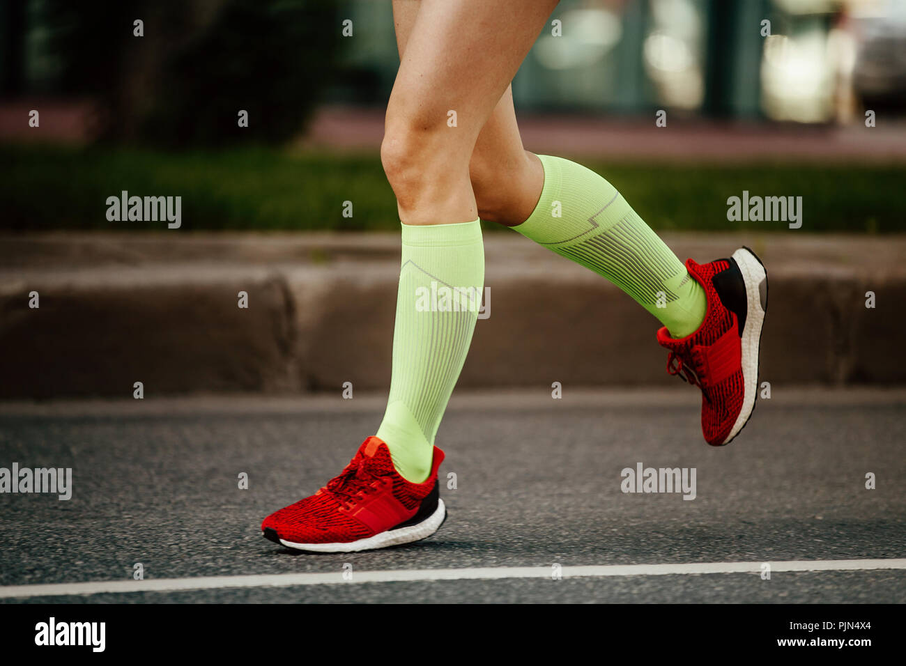 women feet runner in green compression socks and red running shoes ...