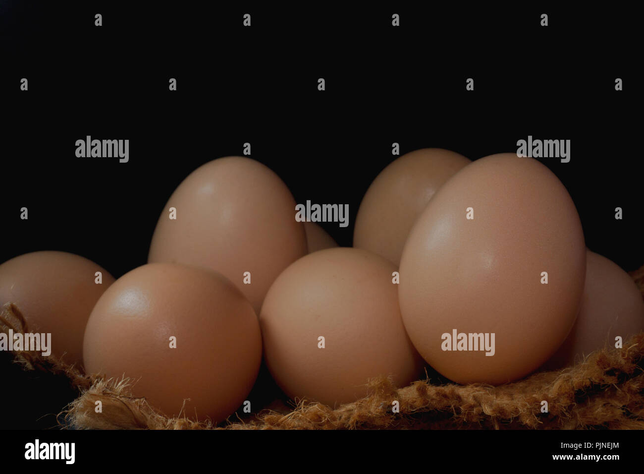 Eggs in a nest on hemp sack, dark corner. Stock Photo