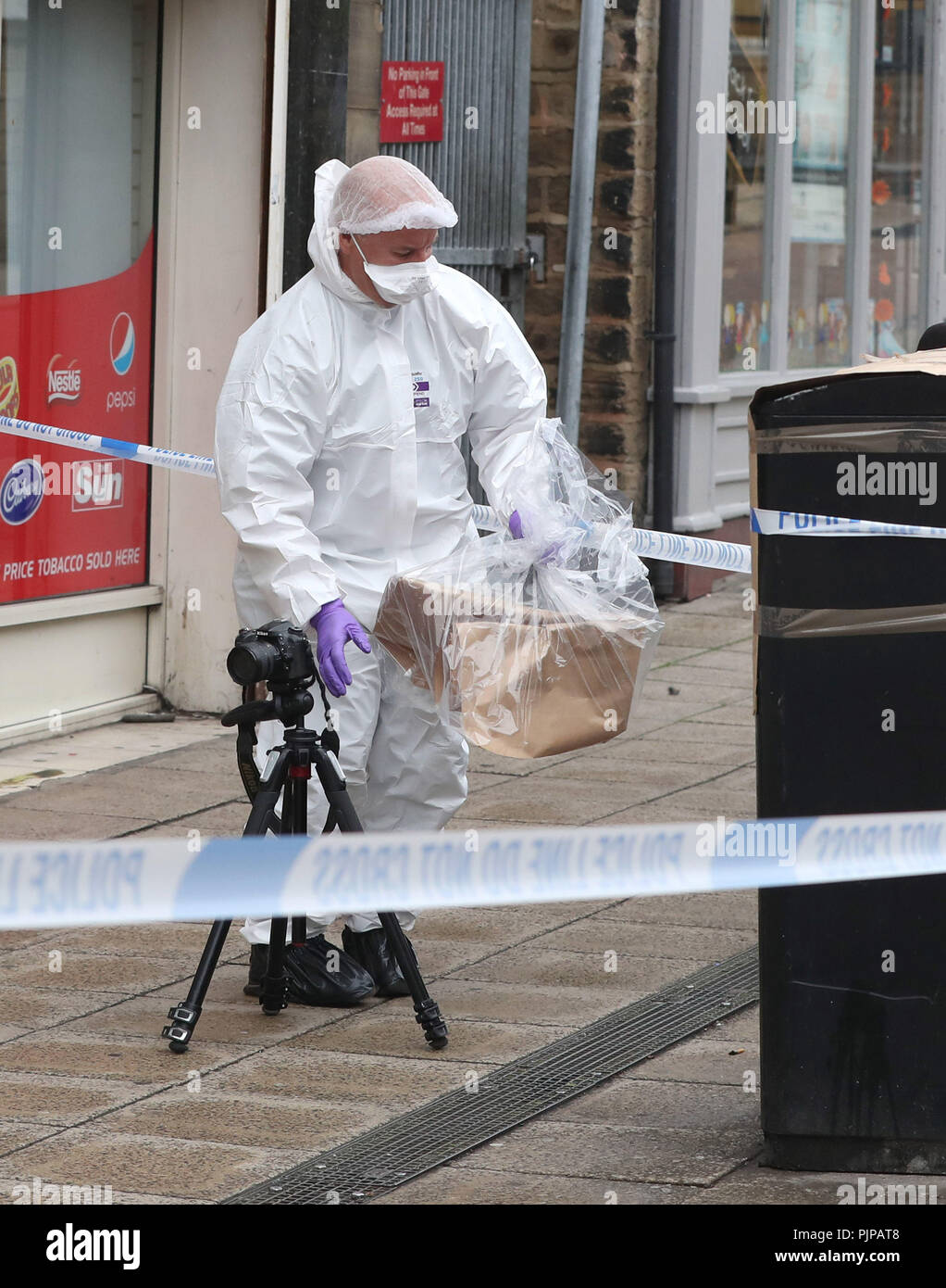 A forensic officer check a bin in Peel Square in Barnsley town centre after a serious incident. Stock Photo
