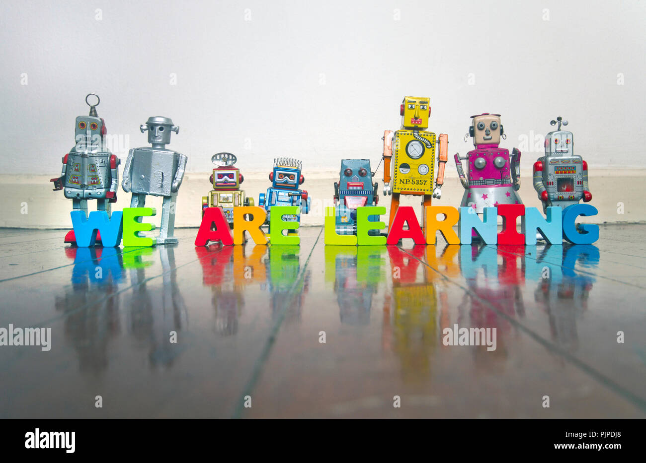 WE ARE LEARNING wooden letters and retro robot toys on a wooden floor with reflection Stock Photo