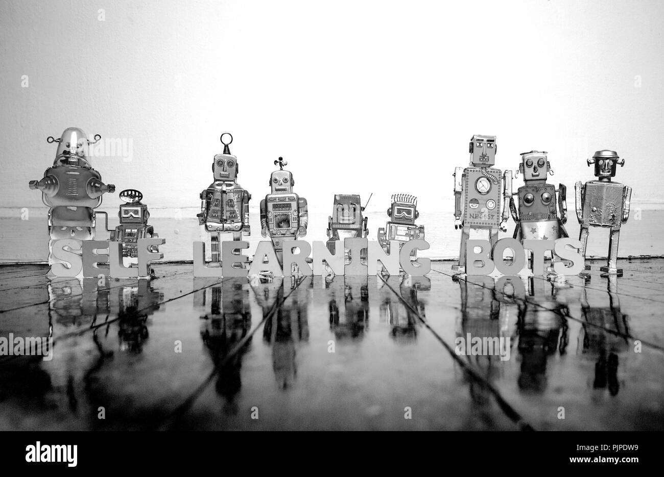 COMPUTER PROGRAMMING wooden letters and retro robot toys on a wooden floor with reflection solarized monochrome Stock Photo