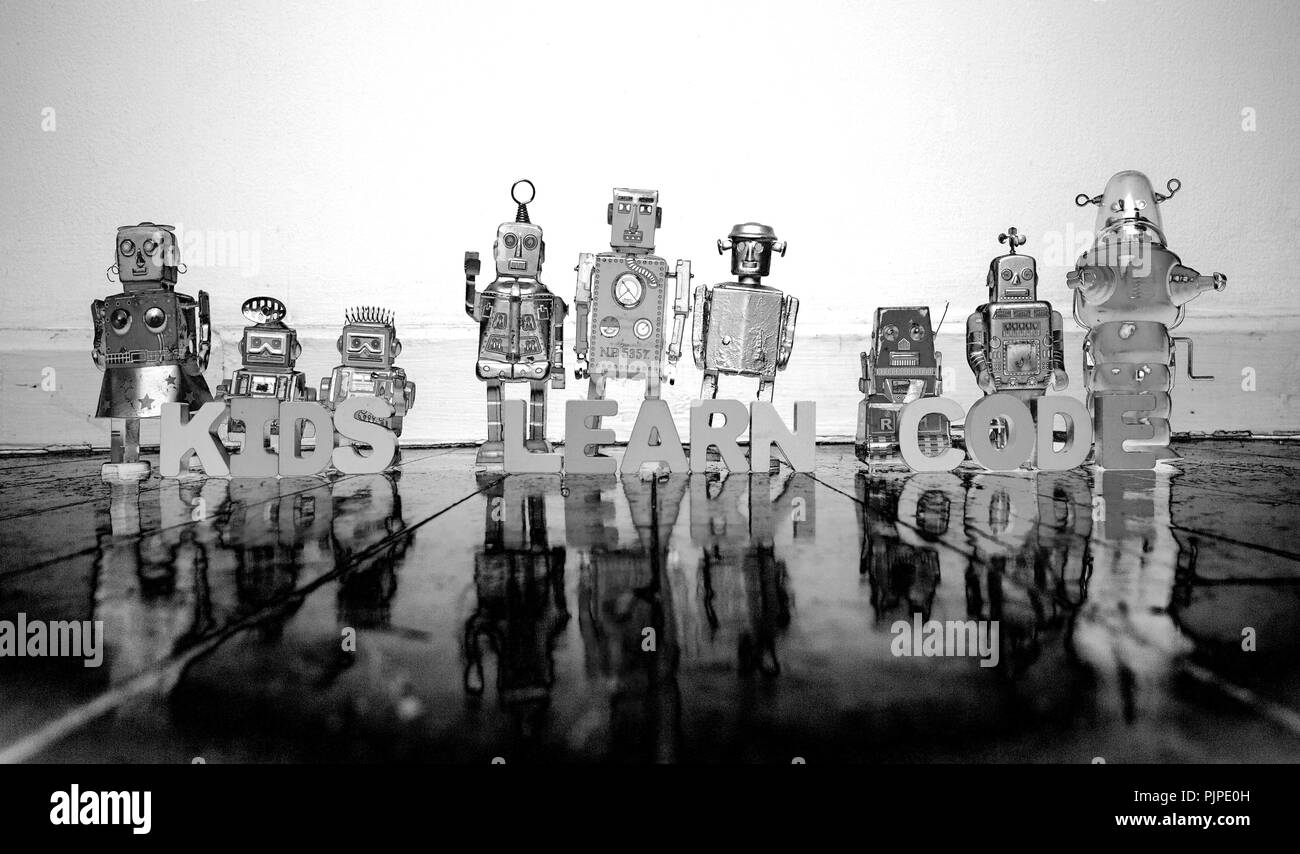 COMPUTER PROGRAMMING wooden letters and retro robot toys on a wooden floor with reflection solarized monochrome Stock Photo