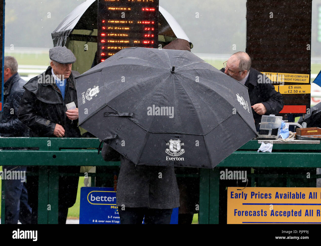 A race goer places a bet in the heavy rain during 32Red Sprint Cup Day at Haydock Park, Newton-Le-Willows. Stock Photo