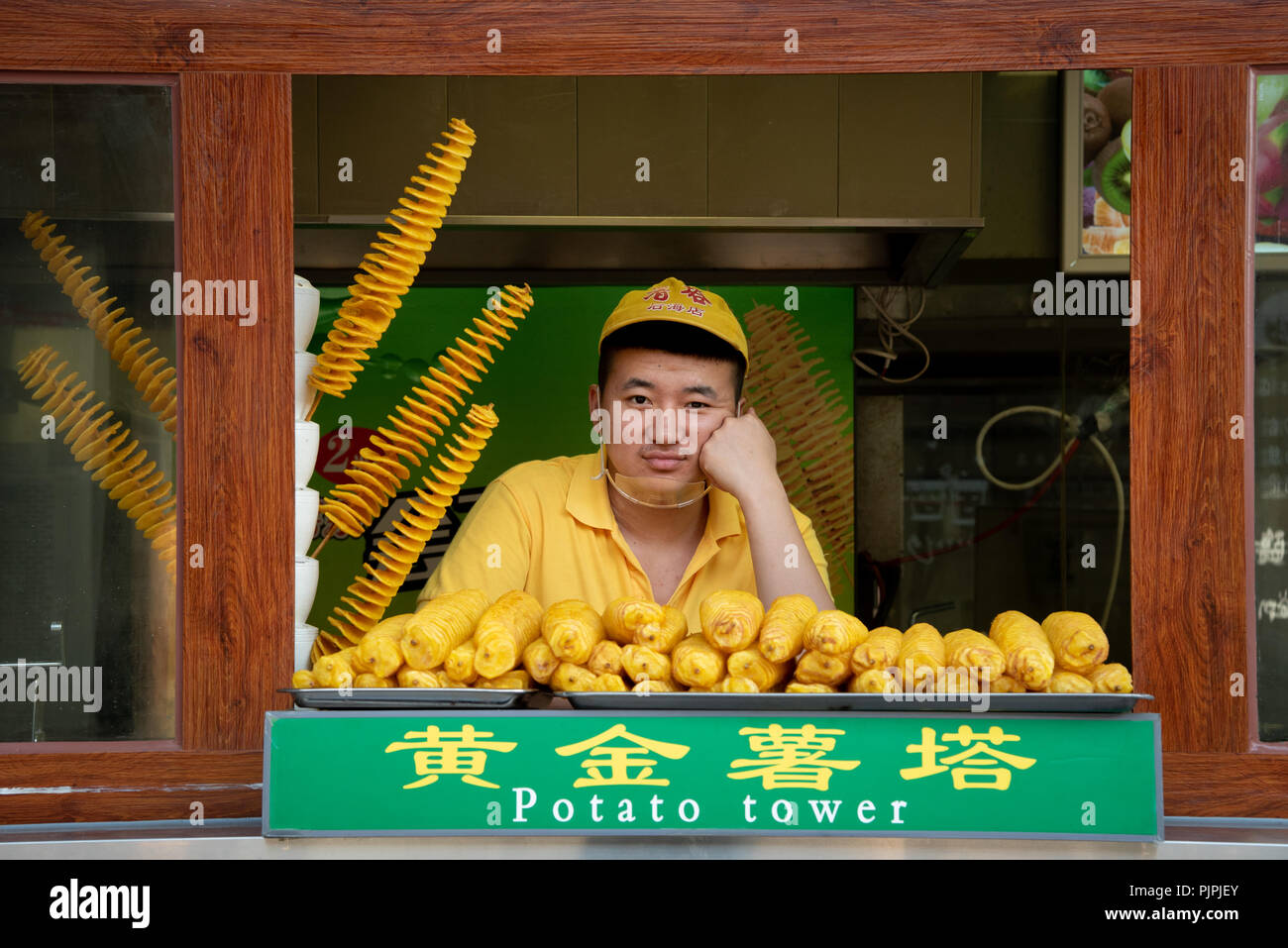 Beijing, China – June 6 2018: Chef in a yellow uniform selling  traditional Chinese  food on a streetmarket at Beijing in China Stock Photo