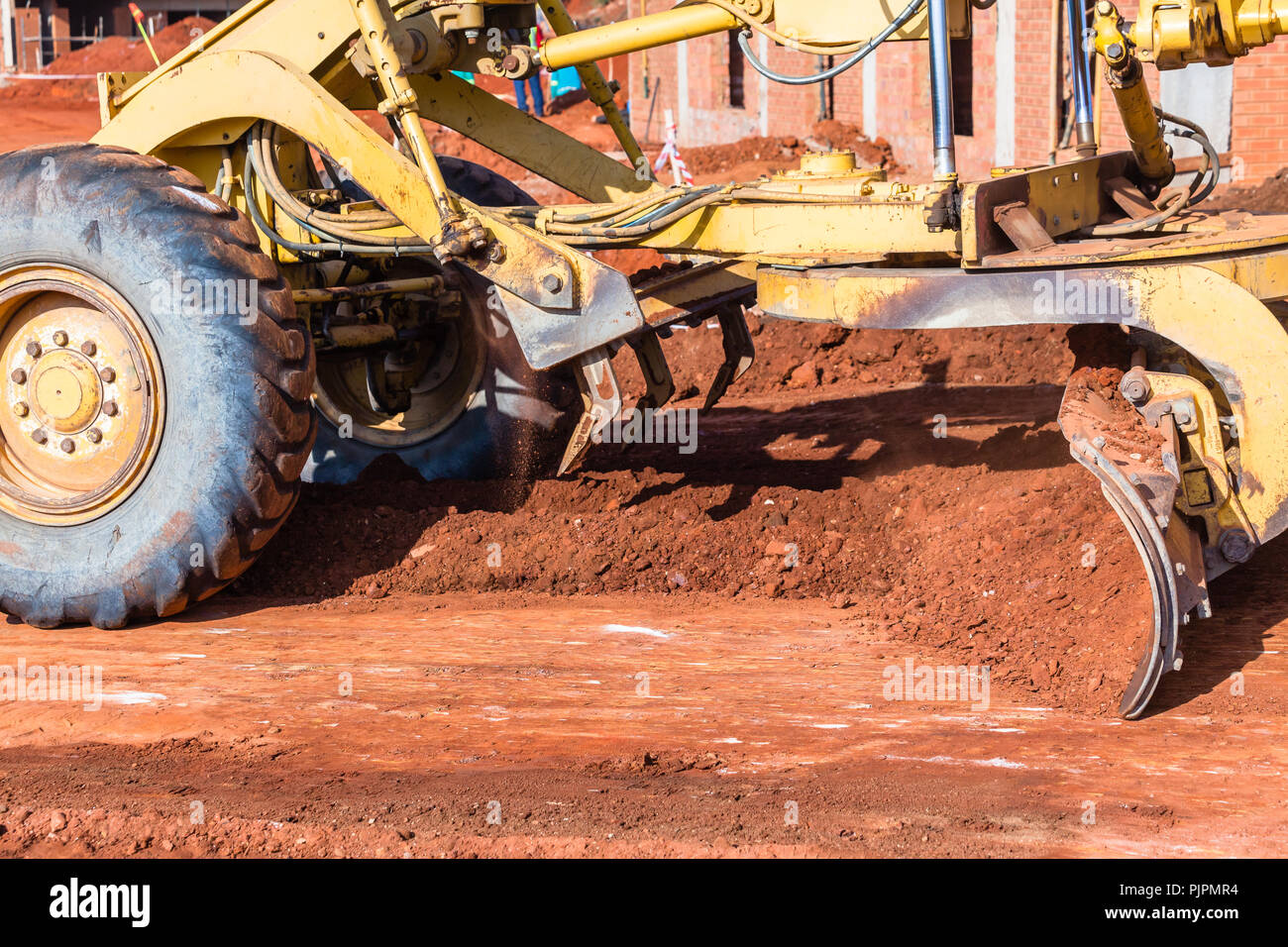 Construction earthworks grader machine blade scoop closeup moving pushing  earth on road layout building site. Stock Photo
