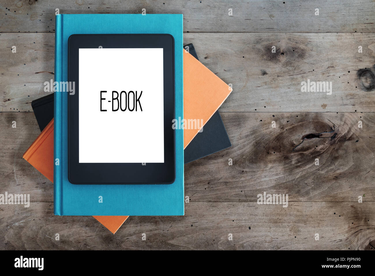 e-book reader on a stack of books on rustic wooden table concept Stock Photo
