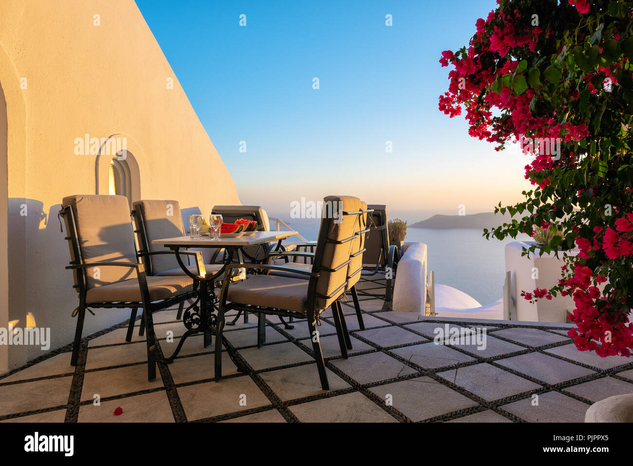 Patio with table and chairs decorated with beautiful bougainvillea flowers at Santorini island, Greece Stock Photo