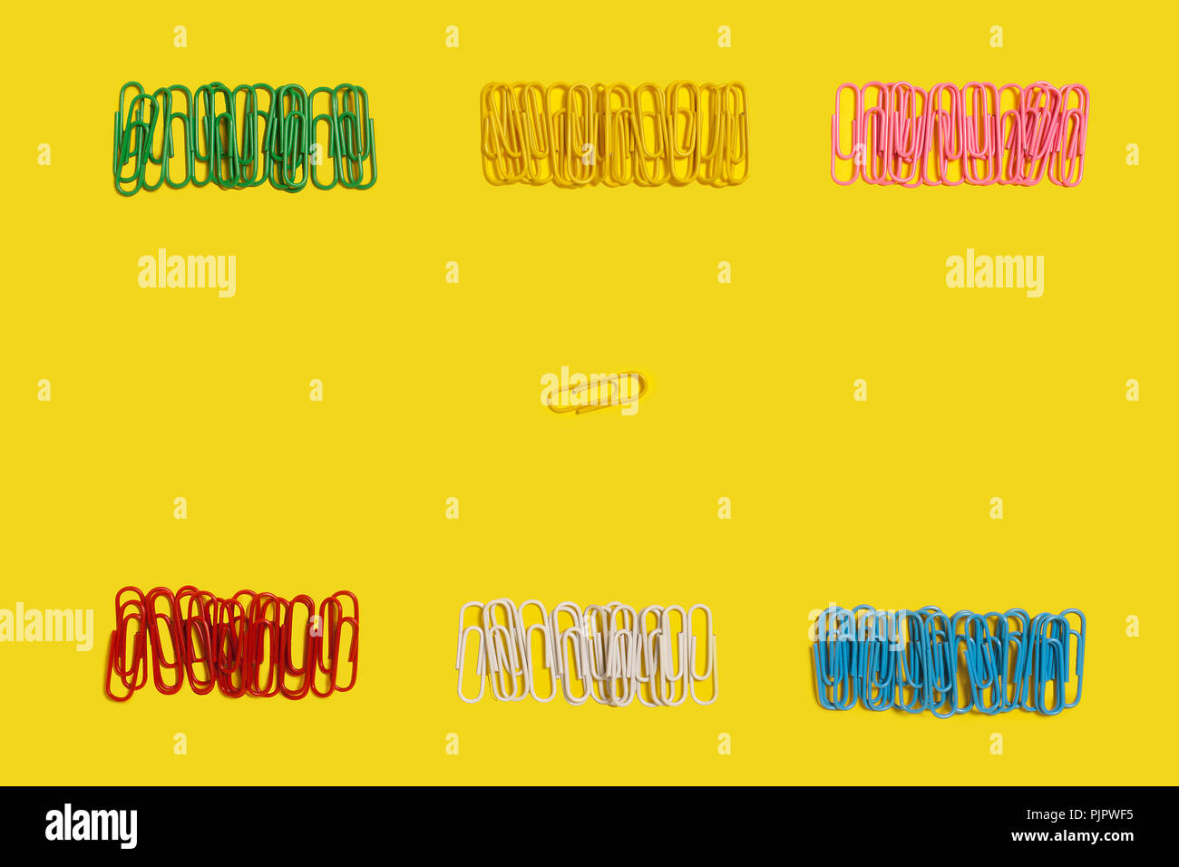 diversity of different in colours paper clips lying on a yellow background. free space for advertising text. concept of office chancery Stock Photo