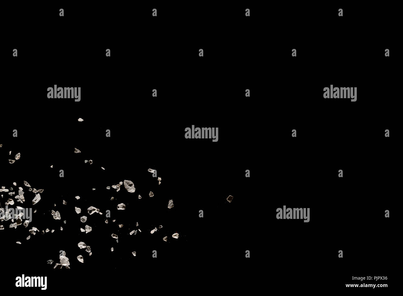Split debris of stone exploding against black background. Stock Photo