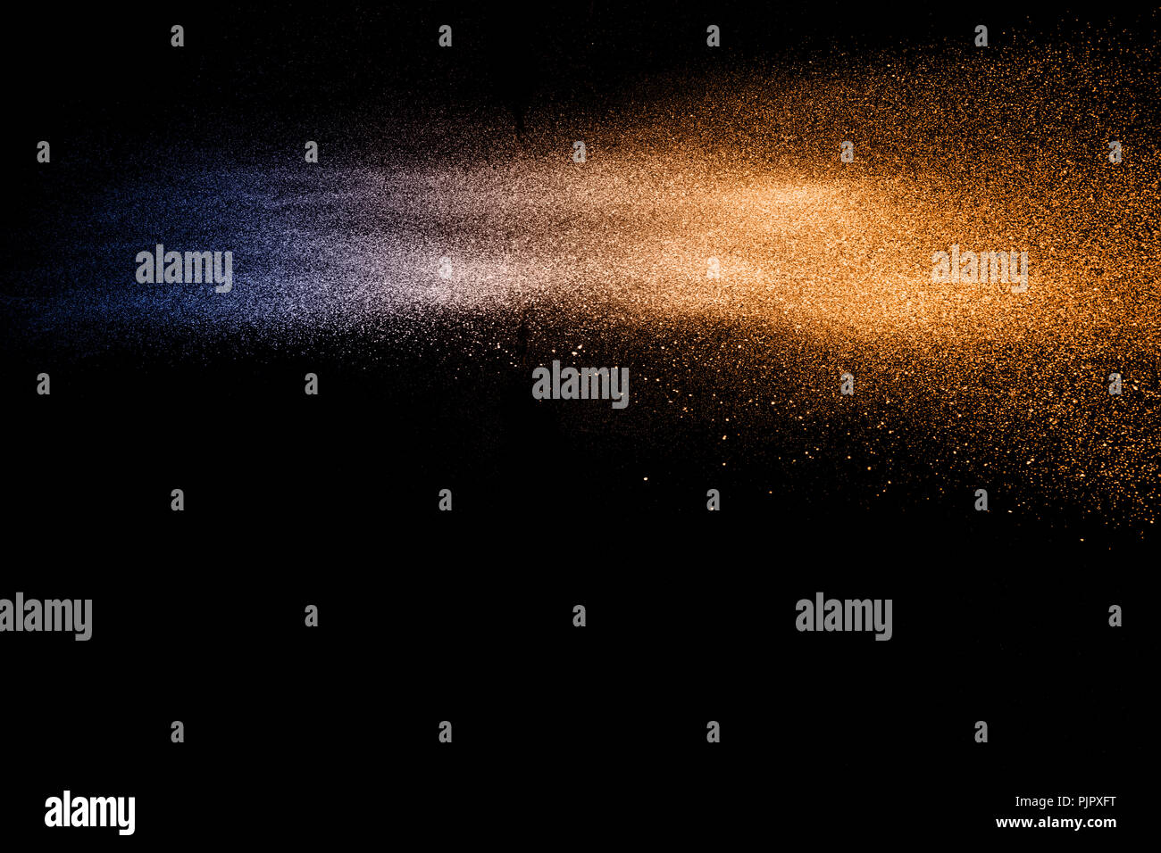 Blue orange dust particles explosion on black background. Color powder dust splash. Stock Photo