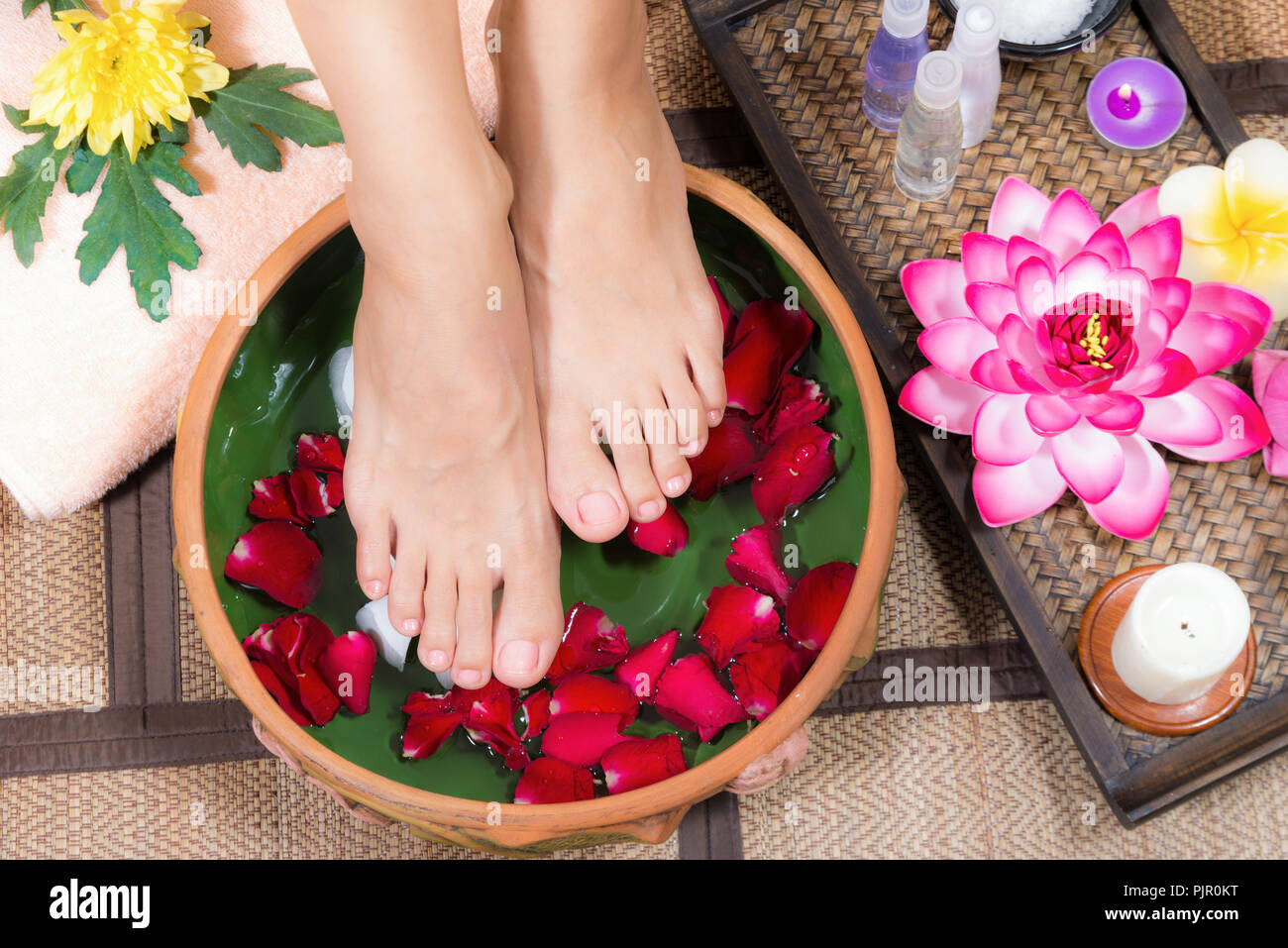 Closeup shot of a woman feet dipped in water with petals in a wooden