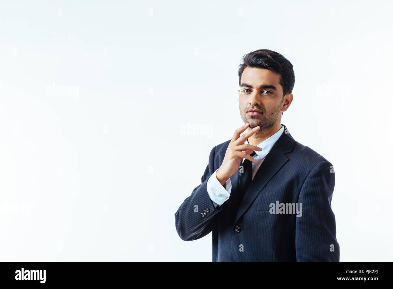 Portrait of a good looking businessman with one finger on his chin. isolated on white background Stock Photo