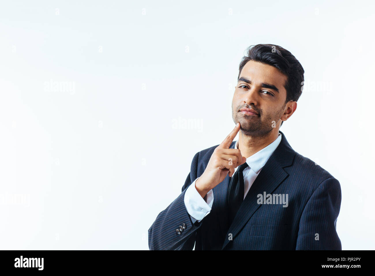 Portrait of a good looking businessman with one finger on his chin. isolated on white background Stock Photo