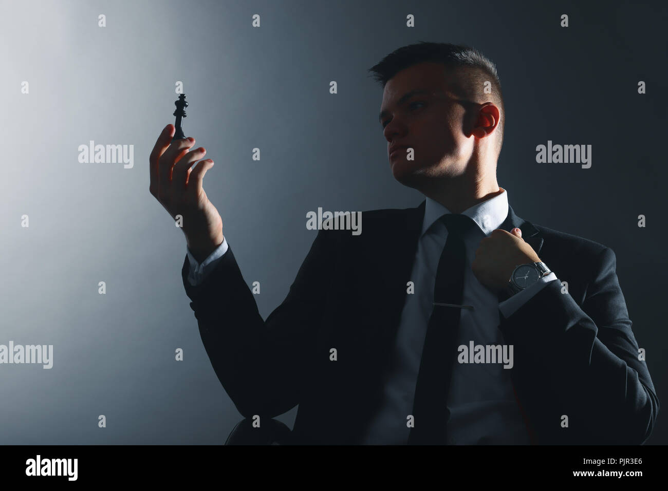 Young businessman looks at a chess piece. Silhouette of the leader. Stock Photo