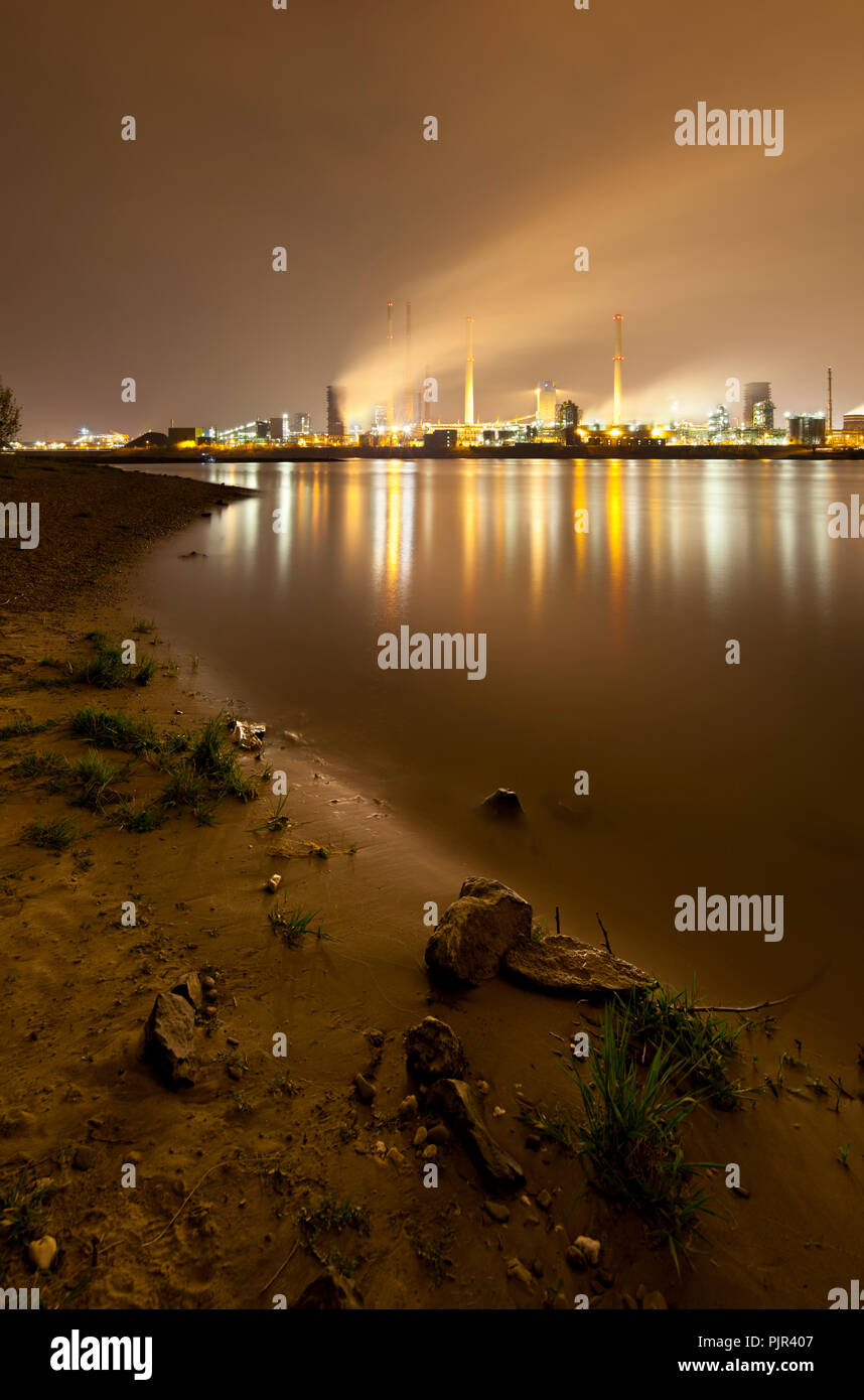 A coking plant seen over a river with a lot of steam, the rivershore in the foreground. Stock Photo