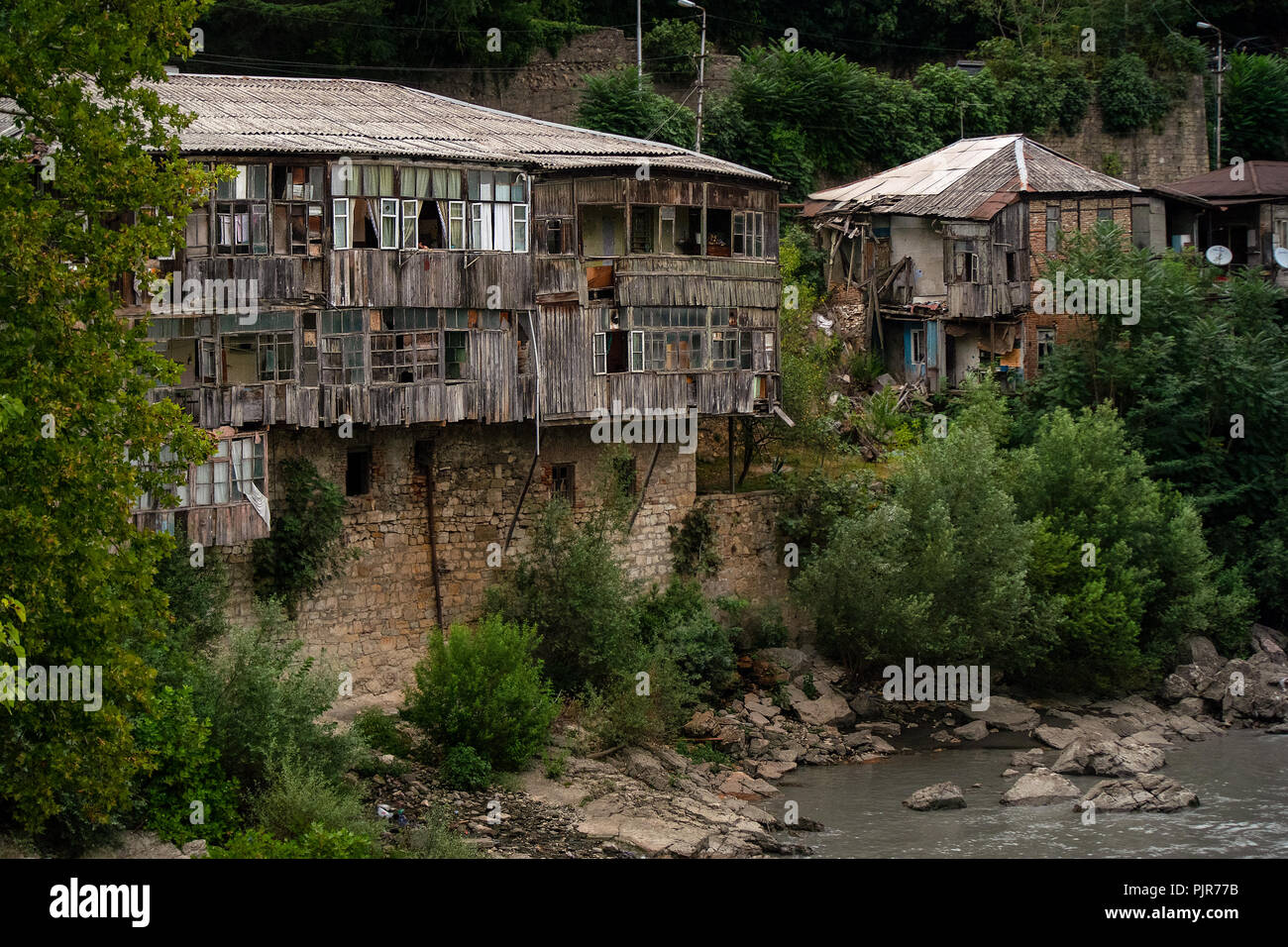 A traditional basic old and in poor condition wood house with a stone reinforced river side house in Kutaisi, Georgia. Stock Photo