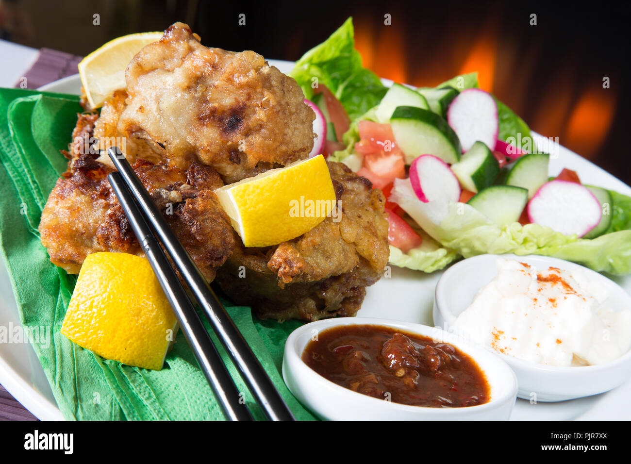 A plated meal of Chicken Karaage with red chili bean dip and Paprika yogurt served with a fresh mixed salad Stock Photo