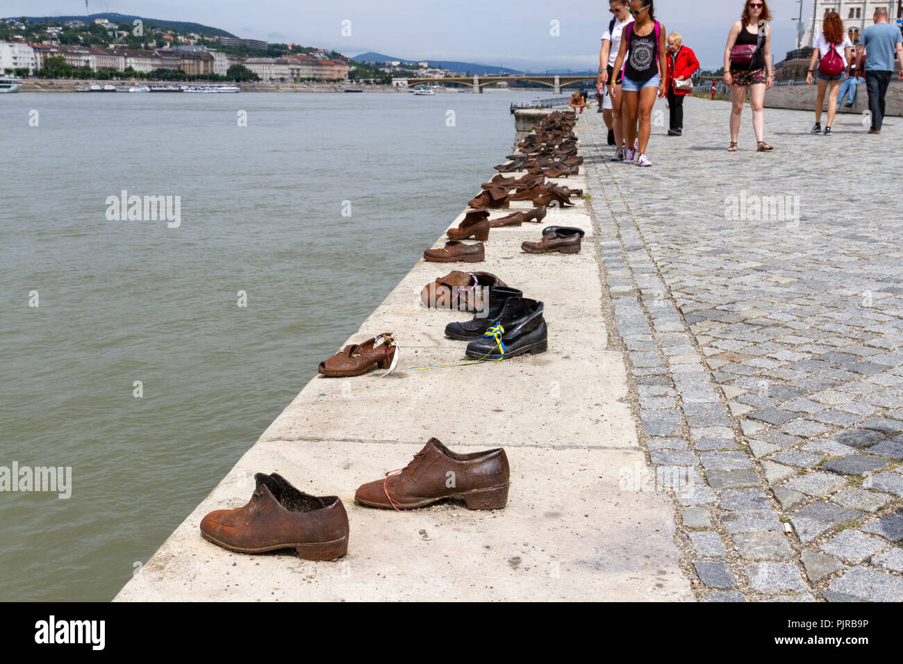 Tourists visiting the Shoes on the Danube Bank Memorial, conceived by Can Togay sculpted by Gyula Pauer, River Danube, Budapest, Hungary. Stock Photo