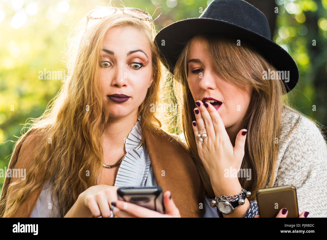 Gossip girl looking at smart phone in the park at sunset Stock Photo