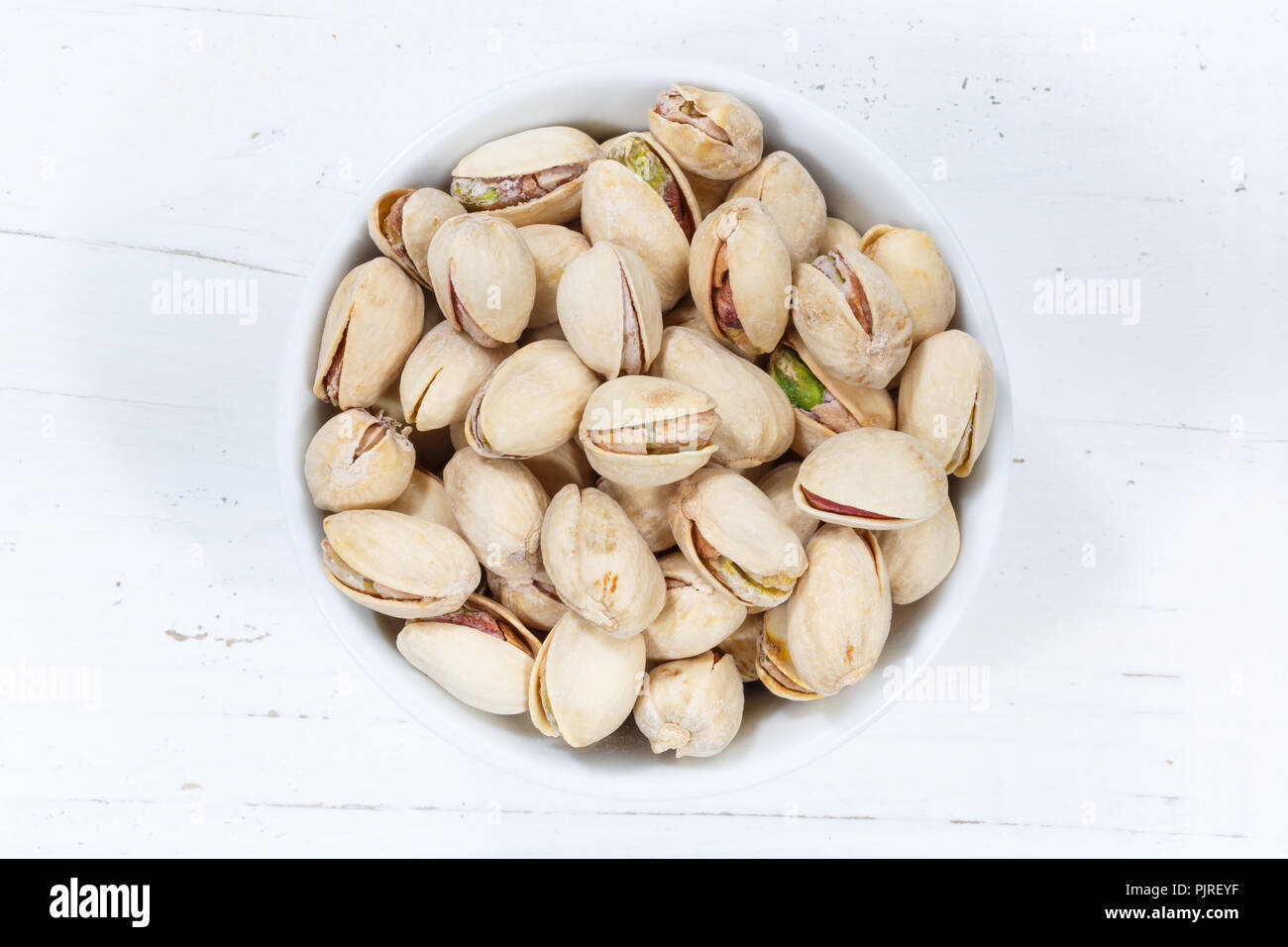 Pistachios pistachio nuts from above bowl wooden board wood Stock Photo