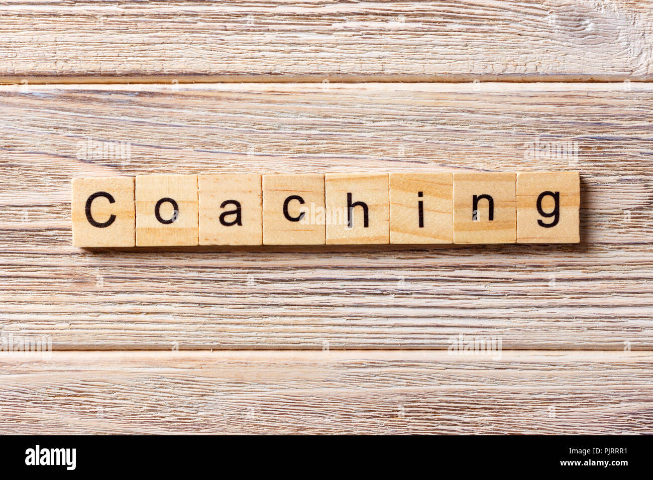 COACHING word written on wood block. COACHING text on table, concept