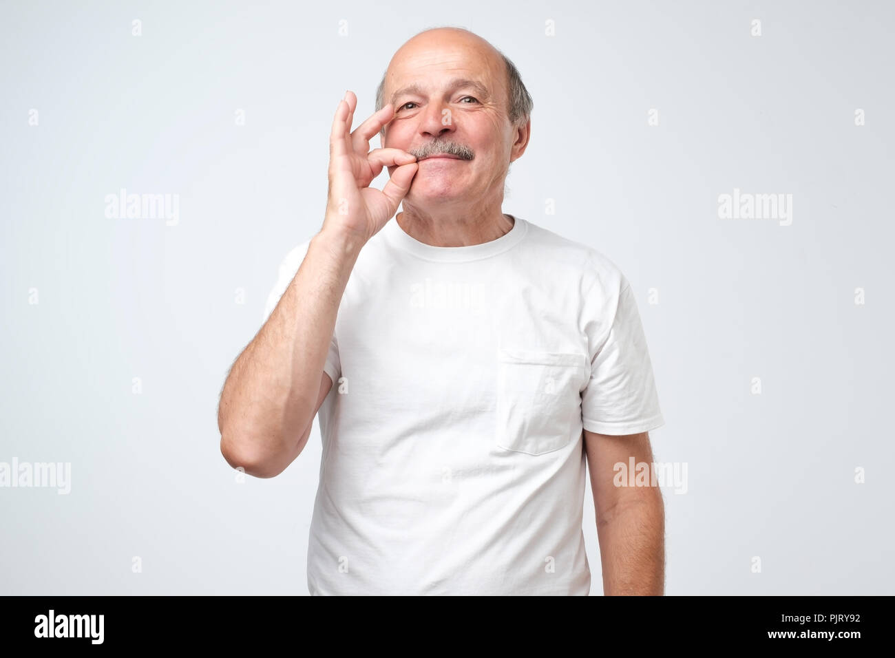 Senior caucasian man showing a sign of closing mouth and silence gesture doing like closing his mouth with a zipper Stock Photo