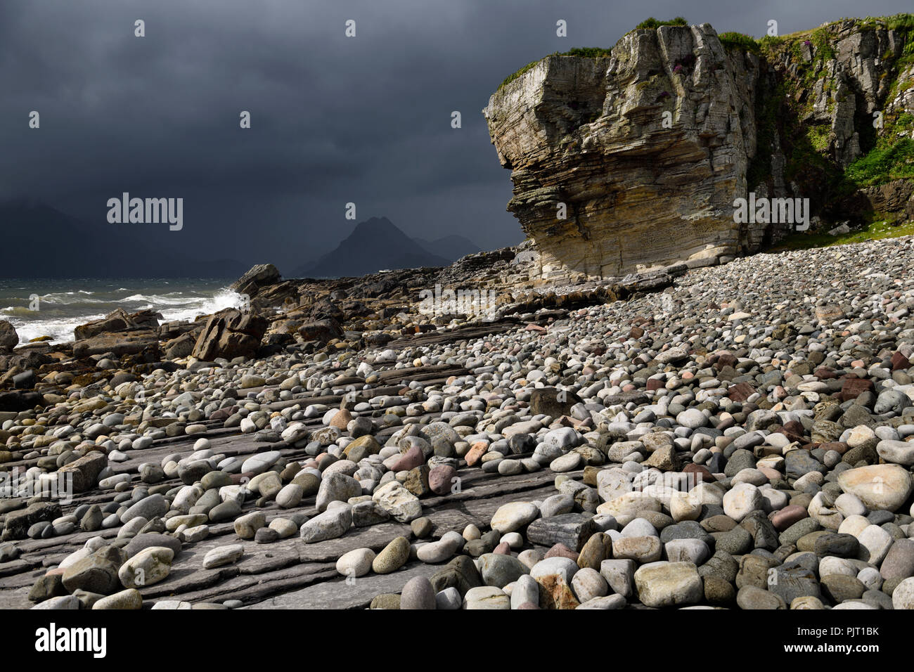 Smooth boulders of Elgol beach at Port na Cullaidh with Red Cuillin Mountains under clouds on Loch Scavaig Isle of Skye Scotland UK Stock Photo