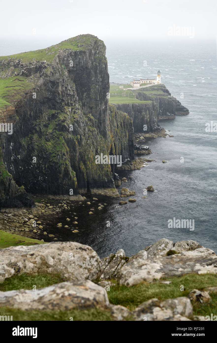 Neist Point Lighthouse in high winds and rain with sheer basalt cliffs to Oisgill Bay Atlantic Ocean Isle of Skye Scotland UK Stock Photo
