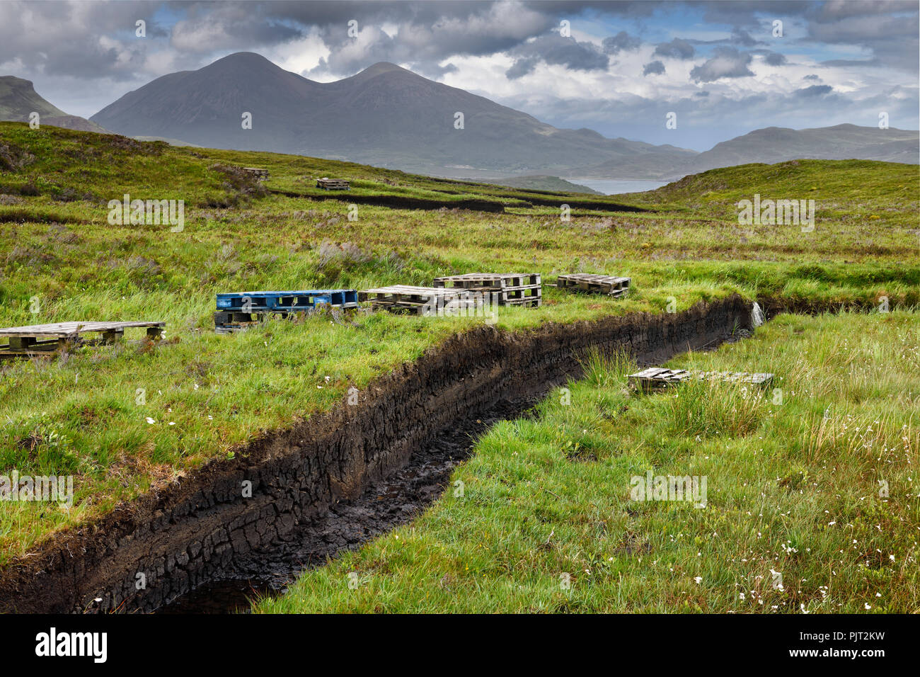 Trenches cut into deep Peat of wetland moors near Drinan on Isle of Skye Scotland with Loch Slap and Beinn Dearg Mhor and Beinn Na Caillich peaks Stock Photo