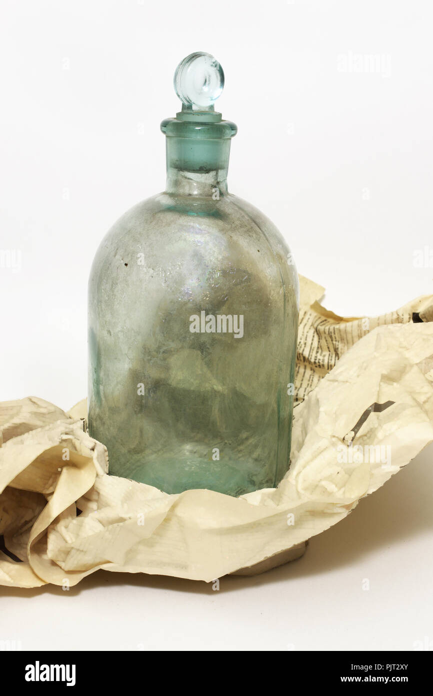 vintage bottle. chemical vessel, corked glass stopper, was wrapped in crumpled newspaper sheet