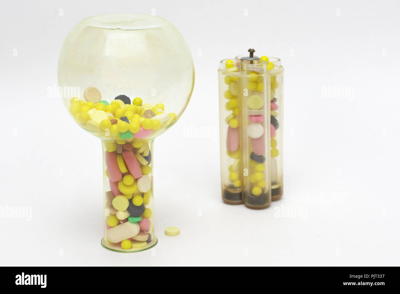 multicolored pills or tablets in upsidedown yellow glass lab flask and